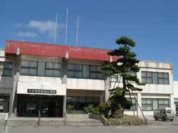 白い外壁の2階建ての建物で玄関上が一部レンガ色になっており、玄関前には立派な松の木が植えられた森田公民館の外観写真