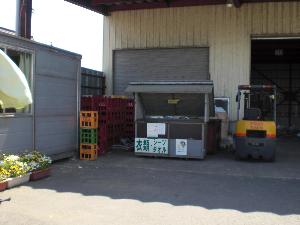 倉庫のような大きな建物の前に設置されている衣類・シーツタオル回収ボックスの写真