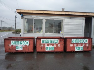 赤褐色の大型のゴミ箱にそれぞれ「古紙回収BOX段ボール」、「古紙回収BOX古新聞」、「古紙回収BOX古雑誌」と書かれた古紙回収ボックスが横一列に設置されている写真