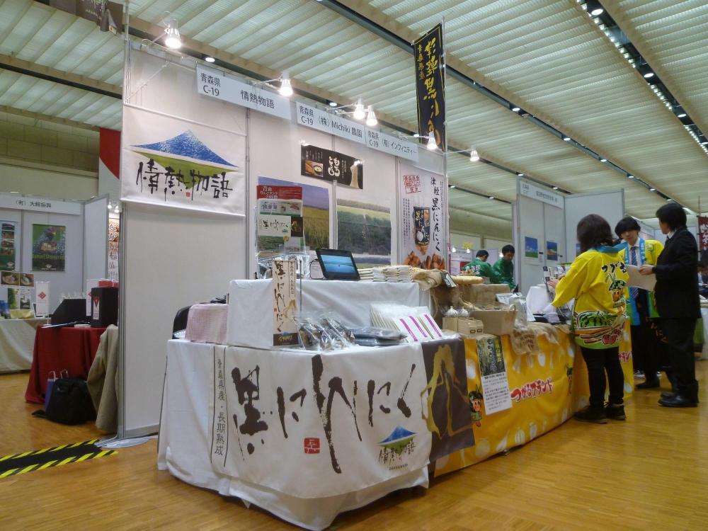 いろいろな商品が展示されボードにも写真やパネルが展示されている青森県のブースを写した写真