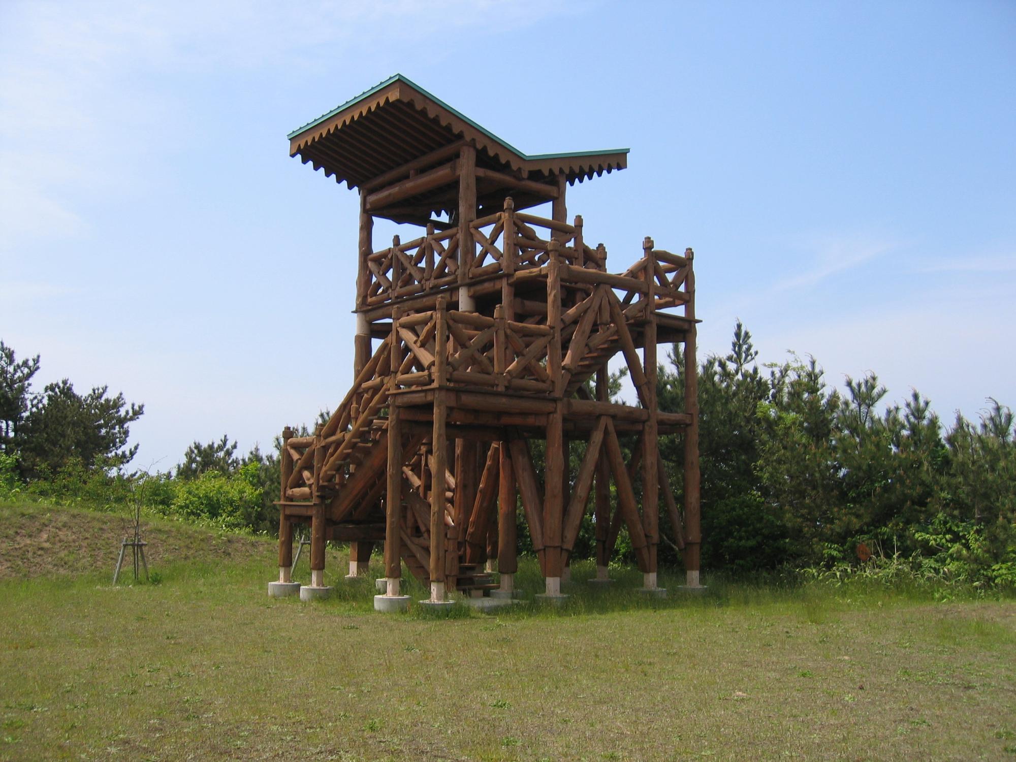 木材の丸太で造られ、回るように階段が作られ展望台に上がっている呑龍岳展望台を写した写真