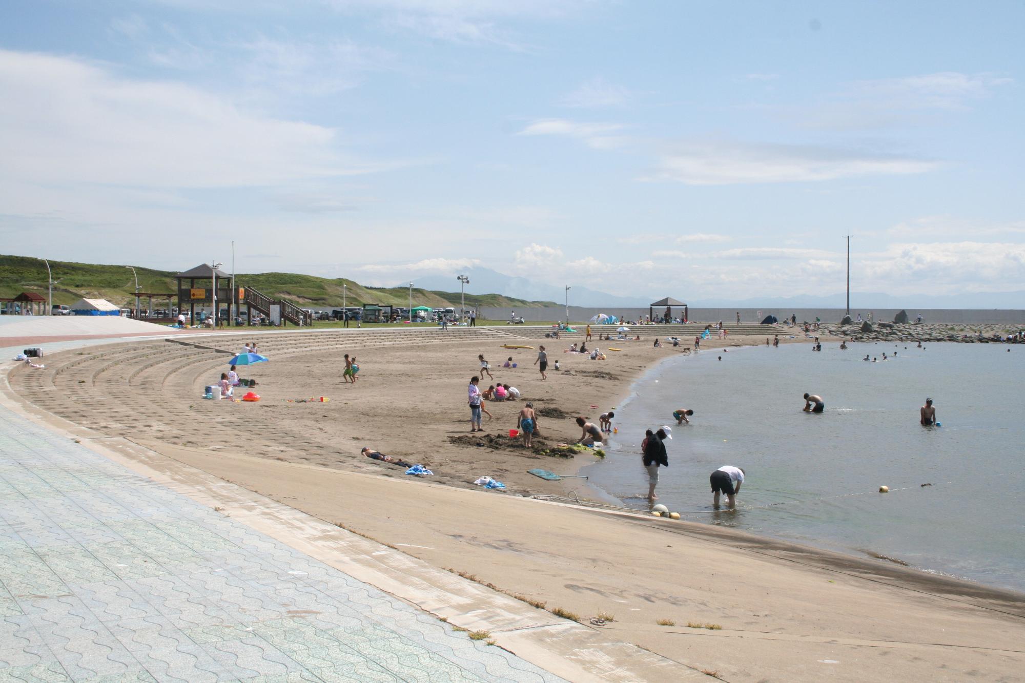 砂浜と海が広がる海水浴場で海水浴を楽しむ人々の写真