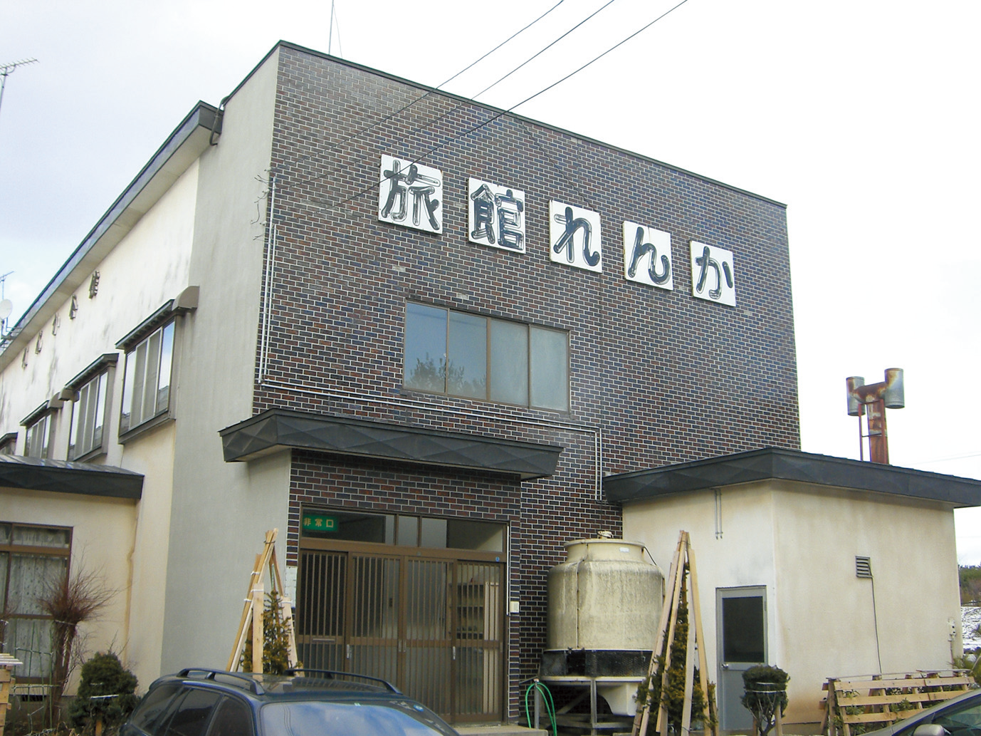 旅館れんかと書かれた一文字ずつの看板がはられている茶色の建物「れんか会館」の外観写真