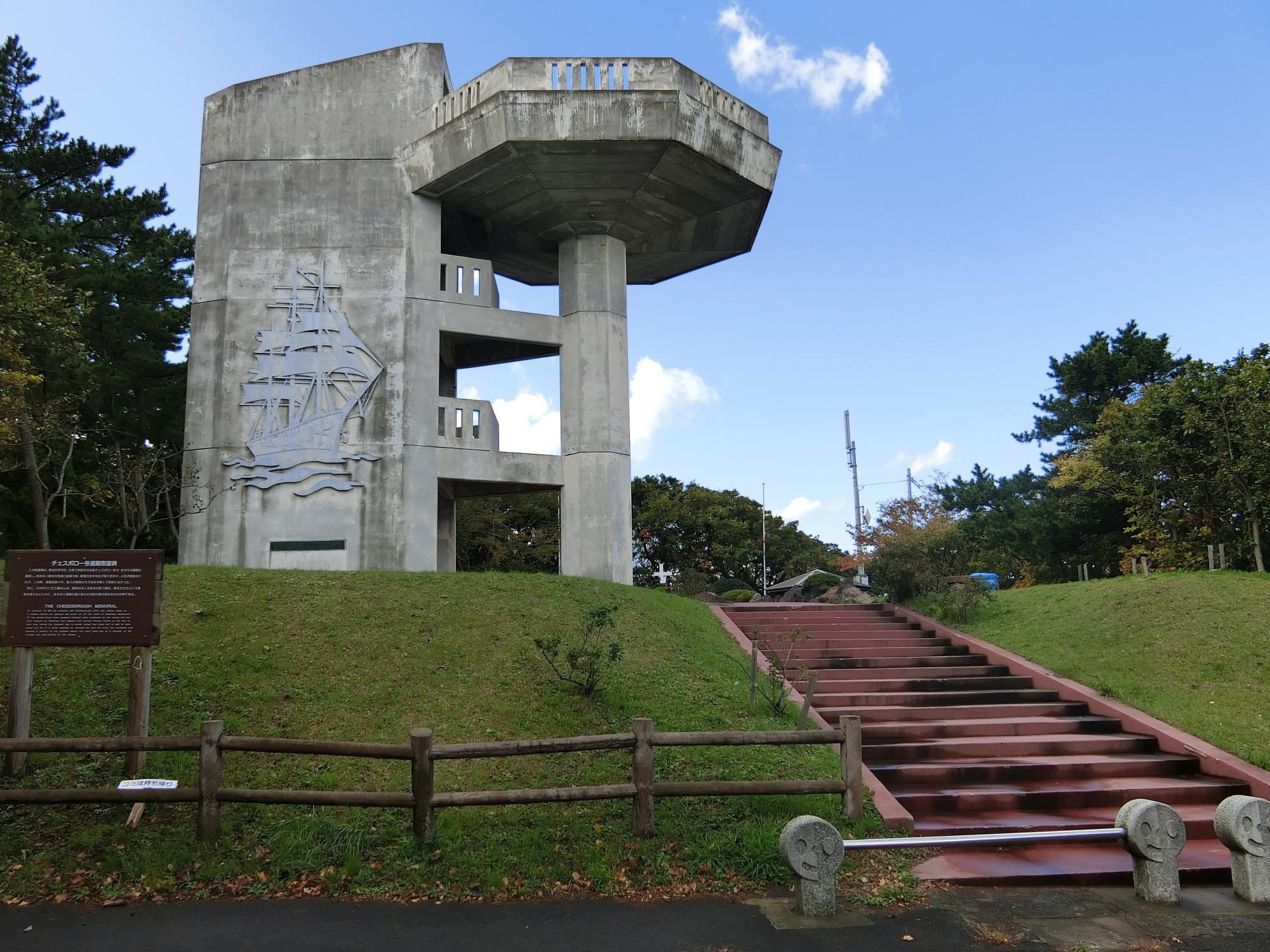 グレーのコンクリート調の建物であり、船のイラストが壁面に描かれている高山小公園の一角に立つ展望台の写真