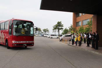 観光バスツアーに向かうバスと見送る人々の写真