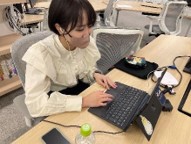 女性がイヤホンを付けノートパソコンの前に座りオンラインワークショップを行っている様子の写真
