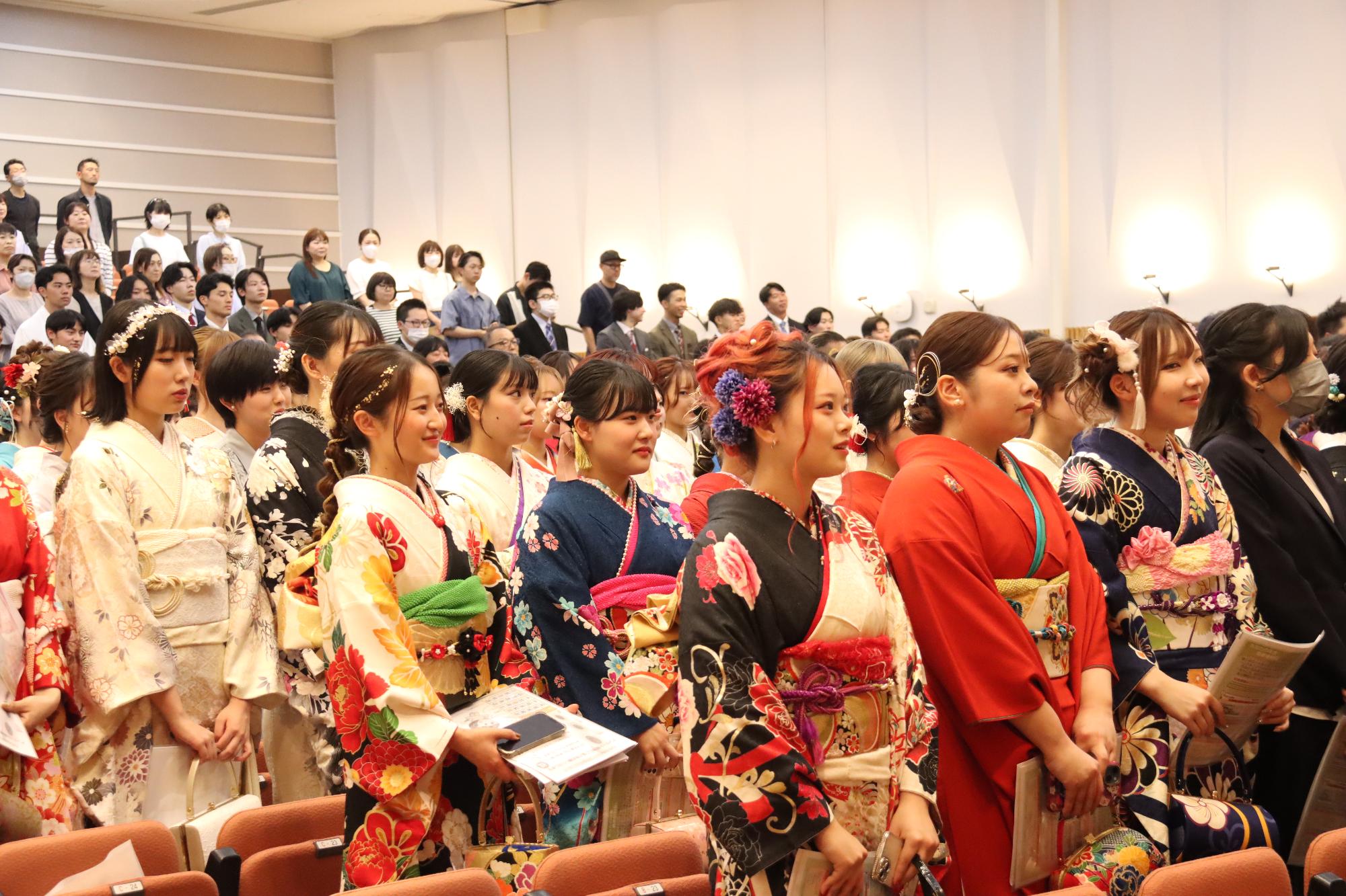 色鮮やかな髪飾りや振袖を着用した参加者が会場で並んでいる写真